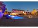 Backyard featuring a pool illuminated with blue lights at dusk, complemented by desert landscaping and exterior lighting at 7736 Tioga Ridge Ct, Las Vegas, NV 89117