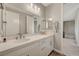 Bright bathroom featuring a dual sink vanity with white cabinets and a large mirror at 7736 Tioga Ridge Ct, Las Vegas, NV 89117
