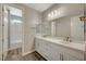 Bathroom featuring dual sinks, white cabinetry, a large mirror, and wood-look tile floors at 7736 Tioga Ridge Ct, Las Vegas, NV 89117