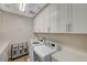 Bright laundry room with white cabinetry, modern washer and dryer, and quartz countertops at 7736 Tioga Ridge Ct, Las Vegas, NV 89117