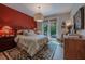 A modern main bedroom with a red accent wall, decorative rug, and access to a private patio at 7988 Pinnacle Peak Ave, Las Vegas, NV 89113