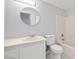 A clean bathroom with a round mirror, a toilet, sink, and a shower over bath at 861 Mcmurray Dr, Pahrump, NV 89060