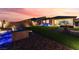 Evening view of the backyard with colorful sunset, artificial lawn, and patio at 10216 Chrysolite Pl, Las Vegas, NV 89143
