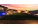 A manicured backyard with an artificial lawn, privacy wall, and landscape lighting at sunset at 10216 Chrysolite Pl, Las Vegas, NV 89143