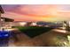 Inviting backyard with lush green lawn, gravel accents, fire pit, and stunning sunset views at 10216 Chrysolite Pl, Las Vegas, NV 89143