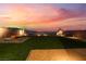 A large, level backyard with artificial lawn, sunset sky, and desert landscaping at 10216 Chrysolite Pl, Las Vegas, NV 89143