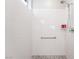 Close up on a white tiled accessible shower with grab bar and pebble base at 10216 Chrysolite Pl, Las Vegas, NV 89143