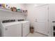 Bright laundry room featuring modern washer and dryer, shelving, and access door at 10216 Chrysolite Pl, Las Vegas, NV 89143