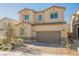 Two-story tan home with a two-car garage, desert landscaping and a brick driveway at 10415 Andele Ave, Las Vegas, NV 89166