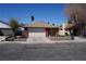 Single-story home with a two-car garage, brick accents, and a well-maintained front yard at 115 Parrish Ln, Las Vegas, NV 89110