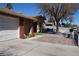 Single-story home with a two-car garage, brick accents, and a landscaped front yard at 115 Parrish Ln, Las Vegas, NV 89110