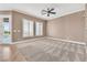 Spacious living room featuring neutral carpet, ceiling fan, and natural light from multiple windows at 11730 Stonewall Springs Ave, Las Vegas, NV 89138