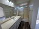 Modern bathroom featuring a vanity with double sinks, a shower with sliding glass doors, and wood-look flooring at 1308 Dusty Creek St, Las Vegas, NV 89128
