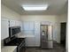 Well-lit kitchen boasts stainless steel appliances and light gray cabinets with door to a bathroom at 1308 Dusty Creek St, Las Vegas, NV 89128