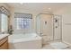 Bathroom featuring a soaking tub, glass block window, and a glass shower at 2021 Evansdale St, Henderson, NV 89052