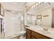 Bright bathroom featuring a glass-enclosed shower, a sink with a wooden cabinet, and an illuminated mirror at 2021 Evansdale St, Henderson, NV 89052