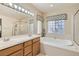 Bright bathroom featuring a double sink vanity, soaking tub, and a clear glass shower at 2021 Evansdale St, Henderson, NV 89052
