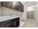 Functional laundry room with sink, storage cabinets, and open shelving at 3428 Royal Calloway Ave, Las Vegas, NV 89141