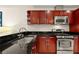 Close-up of kitchen sink, stainless appliances, and dark countertops paired with cherry cabinets, showcasing a practical design at 4575 Dean Martin Dr # 1605, Las Vegas, NV 89103