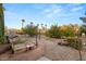 Landscaped backyard with gravel, a walking path, mature trees, desert plants, and stone benches at 4775 N Tee Pee Ln, Las Vegas, NV 89129