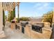 Well-equipped outdoor kitchen with built-in grill, pizza oven, and counter space for alfresco dining at 4775 N Tee Pee Ln, Las Vegas, NV 89129