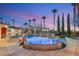 Backyard oasis featuring a pool, spa, and lush landscaping, illuminated under a vibrant twilight sky at 4775 N Tee Pee Ln, Las Vegas, NV 89129