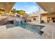 Backyard pool featuring waterfall, stairs to upper patio, outdoor kitchen, and lush landscaping at 540 Regents Gate Dr, Henderson, NV 89012