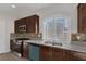 Modern kitchen featuring granite counters, stainless steel appliances, and brown cabinetry at 5977 Ancient Peaks Ave, Las Vegas, NV 89141