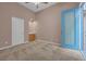 A carpeted bedroom featuring neutral walls, a ceiling fan, and a blue patio door at 8216 Swallow Falls St, North Las Vegas, NV 89085