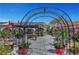 Inviting backyard featuring a decorative metal archway, large paved patio, and a shaded gazebo for outdoor relaxation at 8365 Haven St, Las Vegas, NV 89123