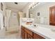 Bright bathroom with shower and bath featuring white tile, and a wood vanity with a white countertop at 879 Judi Pl, Boulder City, NV 89005