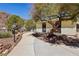 Exterior view of home featuring walkway, desert landscaping, wrought iron fence, and mature trees at 879 Judi Pl, Boulder City, NV 89005