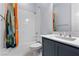 Clean bathroom with white shower tiles, gray vanity and decorative orange shower curtain at 10158 Super Jovian St, Las Vegas, NV 89143