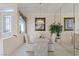 Well-lit dining room with a glass table, upholstered chairs, chandelier, and serene natural light at 10563 Sunblower Ave, Las Vegas, NV 89135