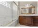 A bathroom with dual sinks, vanity, large mirror, glass enclosed tub and tile accents at 2101 Strada Mia Ct, Las Vegas, NV 89117