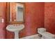 Elegant half bathroom with an ornate framed mirror and antique white sink, pedestal, and toilet at 2101 Strada Mia Ct, Las Vegas, NV 89117