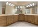 Well-lit bathroom featuring dual sinks, decorative mirrors, sconces and custom cabinetry at 2101 Strada Mia Ct, Las Vegas, NV 89117
