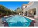 Beautiful backyard pool with brick trim, lush landscaping, and adjacent two story home at 2101 Strada Mia Ct, Las Vegas, NV 89117