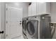 Laundry room equipped with white cabinetry, modern washer and dryer, and a door at 2613 Country Mile Dr, Las Vegas, NV 89135
