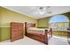 Comfortable bedroom with green walls, wood furniture, large arched window and a ceiling fan at 2726 Manteno Ct, Henderson, NV 89052
