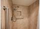 A close-up showcases the stone-tiled standing shower equipped with supportive metal bars at 3287 Southridge Ave, Las Vegas, NV 89121