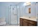 Bathroom with stand-up shower with glass door, wood vanity, and light blue walls at 416 Wyoming St, Boulder City, NV 89005
