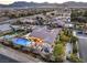 Expansive aerial view of a luxury home featuring a sparkling pool, putting green, and mountain views at 5640 Willow Canyon St, Las Vegas, NV 89149