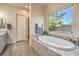 Bright bathroom with large window over the tub, walk-in shower, and granite countertops at 5640 Willow Canyon St, Las Vegas, NV 89149