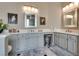 Well-lit bathroom featuring double sinks, white cabinets, marble floors, and decorative artwork at 7432 Tahoe Basin Dr, Las Vegas, NV 89129