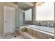 Bright bathroom with a soaking tub, tiled steps, glass-enclosed shower, and decorative lighting at 7432 Tahoe Basin Dr, Las Vegas, NV 89129