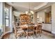 Dining room with a chandelier, ornate table set for six, large windows, and built-in cabinet with mirrored backing at 7432 Tahoe Basin Dr, Las Vegas, NV 89129