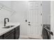 Well-lit laundry room features a sink, modern fixtures, storage, and a front load washing machine at 7695 Windy Meadow Ave, Las Vegas, NV 89178