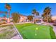 Expansive backyard with a lush lawn, putting green, mature trees, and covered patio at 784 Tossa De Mar Ave, Henderson, NV 89002