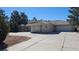 Charming single-story home featuring an attached garage, mature evergreens, and a large concrete driveway at 821 W Amarillo Ave, Pahrump, NV 89048